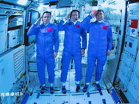 Chinese astronauts salute after successfully entering the Tianhe space station module as they are displayed on a big screen at the Beijing Aerospace Control Center in Beijing.