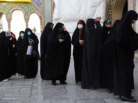 Iranians wait in line to vote at a polling station during presidential elections in Tehran on June 18, 2021.