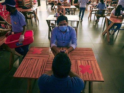 People eat a meal at a food court in Select City Mall after authorities eased a lockdown imposed as a preventive measure against the COVID-19 coronavirus, in New Delhi on June 19, 2021.