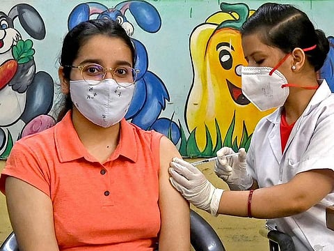 A health worker inoculates a woman with a jab of Covishield's COVID-19 vaccine at a vaccination Centre in New Delhi