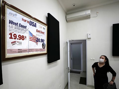 A promotion banner, advertising holiday packages to the US that include a dose of Johnson & Johnson's vaccine, is seen inside a meeting room of Anugerah Tour Semesta travel agency in Jakarta, Indonesia.
