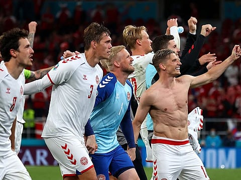 Denmark's players celebrate with fans after the match.