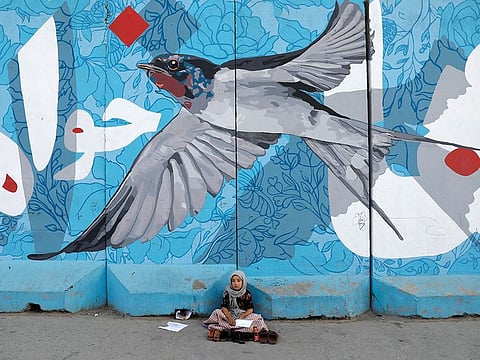 Images that must haunt us all: A shoeshine girl waits for customers under a graffiti in Kabul, Afghanistan (File)