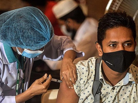 A health worker inoculates a man with a dose of the Oxford-AstraZeneca COVID-19 vaccine at the Bangabandhu Sheikh Mujib Medical University Hospital (BSMMU), in Dhaka.
