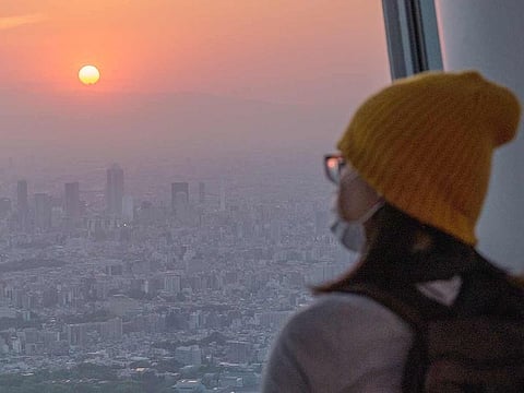 A visitor watching the sunset from the observation deck of the Tokyo Skytree in Tokyo.