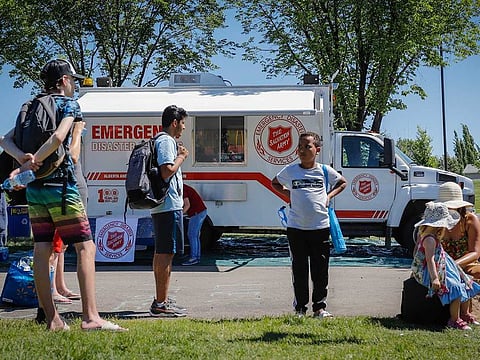 A Salvation Army EMS vehicle is setup as a cooling station as people lineup to get into a splash park while trying to beat the heat in Calgary, Alberta, Wednesday, June 30, 2021.