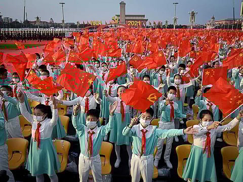 Students wave the Chinese flags before the celebrations marking the 100th anniversary of the founding of the Communist Party of China in Beijing on July 1, 2021.
