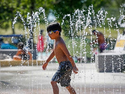 A young boy runs through a fountain at a splash park trying to beat the heat in Calgary, Alberta, Wednesday, June 30, 2021.