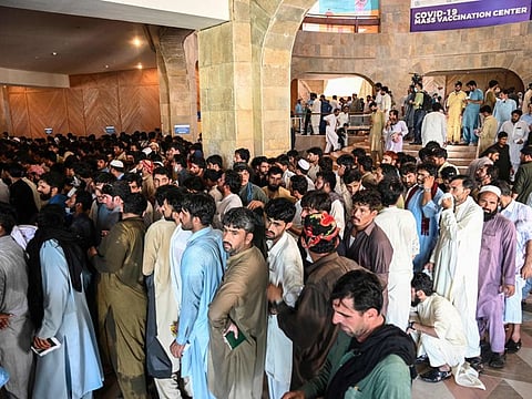 People including overseas Pakistani workers who want to fly to the Middle East stand in a queue to register before receiving a dose of the Pfizer COVID-19 vaccine in Islamabad on June 28, 2021.