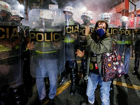 A person holds up a phone in front of riot police during a protest against Brazil's President Jair Bolsonaro, in Sao Paulo, Brazil, July 3, 2021.