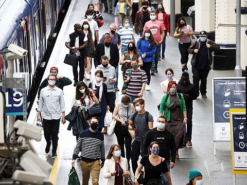 People, some wearing protective face masks, walk through Waterloo Station, in London, on July 4, 2021.