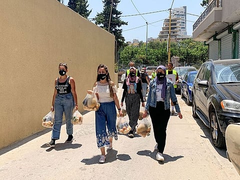 Volunteers from Base Camp, walk as they carry bags of vegetables to be distributed to people in need in Beirut, Lebanon July 1, 2021.