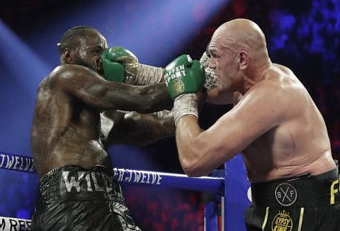 In this file photo, Tyson Fury, right, of England, lands a right to Deontay Wilder during a WBC heavyweight championship boxing match in Las Vegas. Fury has tested positive for COVID-19, and his third bout with Wilder will be postponed, likely until the fall.