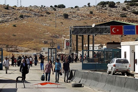 Syrians carry their belongings as they cross back into Syria at the Syrian-Turkish border crossing of Bab Al Hawa in Idlib province in a file photo.