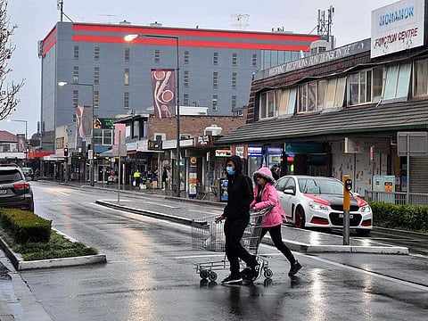 A couple make their way to a supermarket for last minute shopping ahead of new COVID-19 restrictions in the Fairfield suburb of Sydney on July 9, 2021, as lockdown in Australia's largest city was tightened after new COVID-19 infections hit a record and authorities warned an outbreak of the Delta variant was spinning out of control.