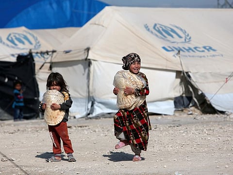 Children holding stacks of bread walk in Al Hol displacement camp in Hasaka governorate, Syria, in a file photo.