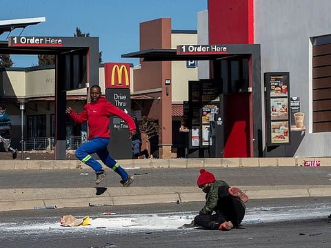 Looters run from police officers at a shopping centre in Soweto, in Johannesburg, South Africa, Tuesday, July 13, 2021.