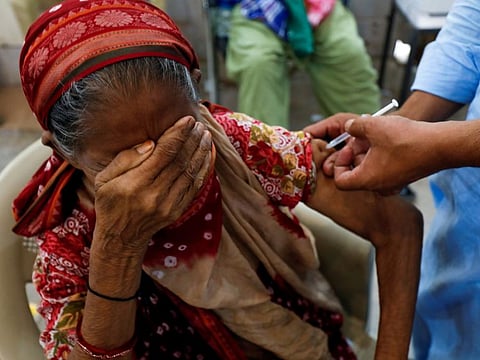 Basanti, 71, reacts as she receives a dose of the COVID-19 vaccine at a vaccination centre in Karachi.