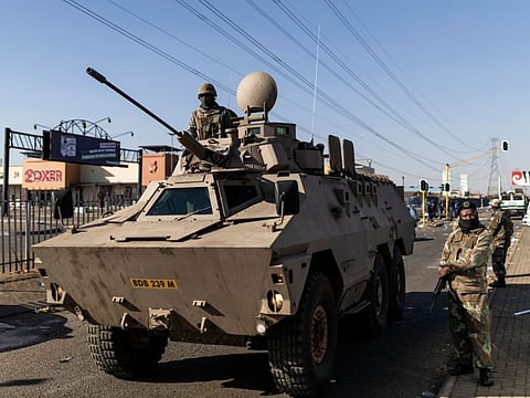 Members of the South Africa Defence Force (SANDF) stand guard with an armoured vehicle outside the Chris Hanni Mall in Vosloorus, on the northern outskirts of Johannesburg, on July 14, 2021.
