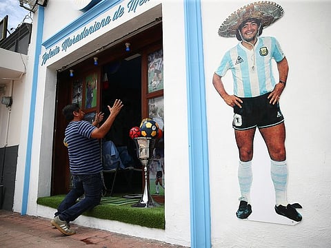 A fan kneels at the entrance to the first Mexico's church in memory of soccer legend Diego Maradona in San Andres Cholula, in Puebla state, Mexico.