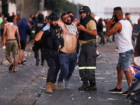 Members of the civil defence help an injured demonstrator during a protest after Lebanese Prime Minister-designate Saad Hariri abandoned his effort to form a new government on July 15, 2021.