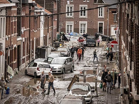 People walk through a damaged street after flooding in Chenee, Province of Liege, Belgium. Severe flooding in Germany and Belgium has turned streams and streets into raging torrents that have swept away cars and caused houses to collapse.