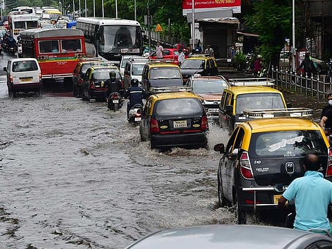 Vehicles make their way through a waterlogged street after heavy rainfall, in Mumbai on Sunday, July 18.