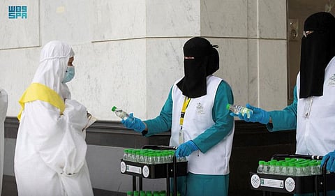 Women workers distribute water to pilgims in the Grand Mosque.