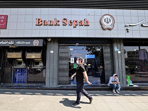 An Iranian man walks past a shuttered Bank Sepah branch in downtown Tehran on July 20, 2021.