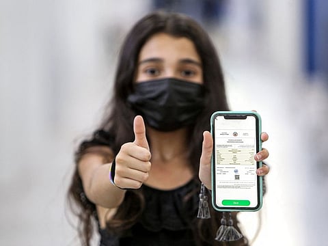 A Kuwaiti teenager holds her phone showing off her COVID-19 vaccination certificate after receiving her shot of the Pfizer-BioNTech vaccine, at a vaccination centre in Kuwait City on July 18, 2021.