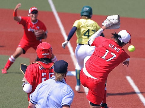 Japan's starter pitcher Yukiko Ueno (R) throws the ball towards first base player (L) during the Tokyo 2020 Olympic Games softball opening round game between Australia and Japan at Fukushima Azuma Baseball Stadium in Fukushima, Japan, on July 21, 2021.