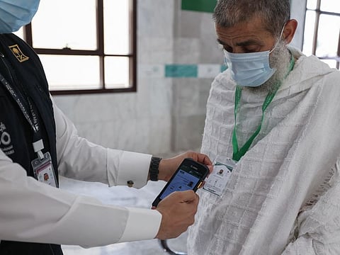 A Saudi member of staff scans a pilgrim's Hajj card, allowing contactless access to religious sites, accommodation and transport, at a reception centre in Mecca on July 18, 2021.