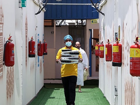 A staff member delivers food portions to pilgrims at their camp in Mina on July 18, 2021. The Saudi Ministry of Hajj and Umrah said the meals did not meet the conditions stipulated in related contracts in terms of preparing and serving the meals.