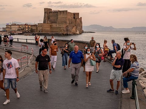 Tourists walk along the promenade near Ovo Castle, also known as Castel dell'Ovo, seaside fortification in Naples, Italy, on July 21, 2021.