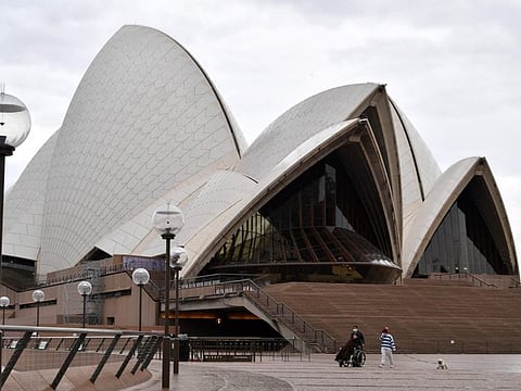 Visitors make their way in front of the iconoic Opera House in Sydney on July 23, 2021, amid a coronavirus outbreak that state leaders said has become a "national emergency".