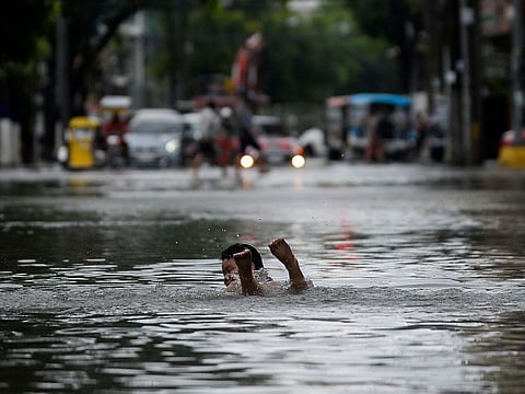 A boy swims on a flooded street following heavy rains, in Manila.