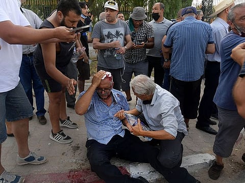 A supporter of the country’s Islamist Ennahda party is injured by a stone thrown at him during a protest outside the parliament building in the capital Tunis on July 26, 2021.