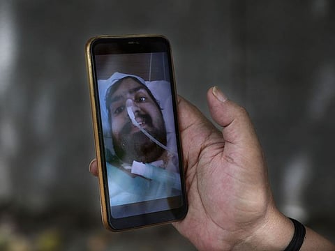 Anil Sharma shows a photograph of his son Saurav who is being treated for COVID-19 at a private hospital in New Delhi, India.