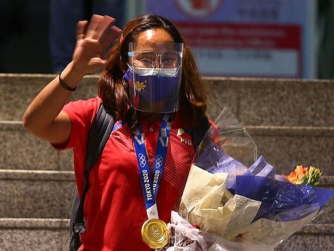 Philippine Olympic gold medallist Hidilyn Diaz waves to photographers as she arrives at the Ninoy Aquino International Airport in Manila on July 28, 2021, following her return to her home country after she won gold in the women's 55kg weightlifting at the Tokyo 2020 Olympics.