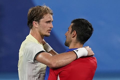 Alexander Zverev (left) of Germany, speaks with Novak Djokovic, of Serbia, after defeating him in the semifinal of the men's tennis competition at the 2020 Summer Olympics in Tokyo, Japan.