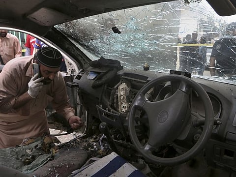 An investigator examines a damaged police vehicle at the site of hand grenade attack, in Peshawar on July 30, 2021.