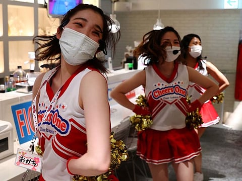 Waitresses perform for customers at the cheerleader-themed bar 'Cheers One' in Tokyo on July 29, 2021. The emergency measures focus on an alcohol ban at eateries and karaoke bars and their shortened hours from Monday to August 31.
