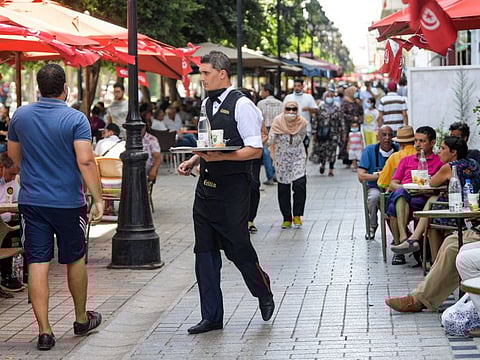 A waiter serves people sitting outdoors by a cafe along the Avenue Habib Bourguiba in Tunisia's capital Tunis on July 28, 2021. Tunisia’s economy last year contracted by more than eight per cent as the pandemic battered the crucial tourism sector.