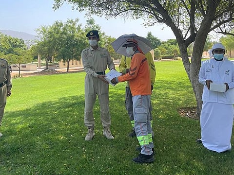 Dubai Police, Spirit of the Union volunteers distribute meals and umbrella hats to workers in Hatta