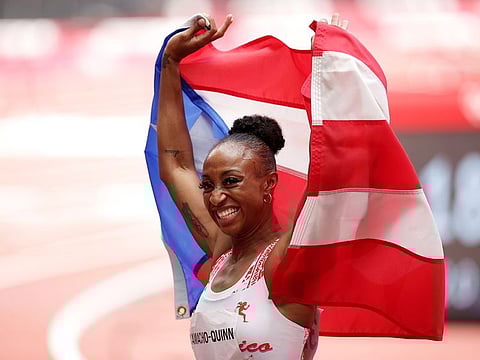 Jasmine Camacho-Quinn of Puerto Rico celebrates with her national flag after winning gold in Women's 100m Hurdles.