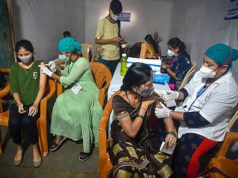 Health workers administer COVID-19 vaccine dose to beneficiaries during a vaccination drive for tribal people at Aarey Colony in Mumbai, Tuesday, August 3, 2021.