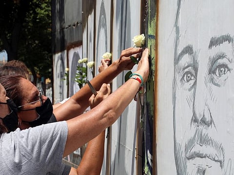 People place white roses on portraits of victims of last year's Beirut port blast as Lebanon marks one year anniversary of Beirut port explosion, on August 3, 2021.