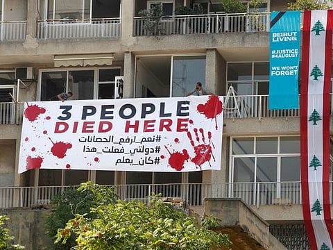 People put a banner on a building as Lebanon marks one year anniversary of Beirut port explosion, in Beirut on August 4, 2021.
