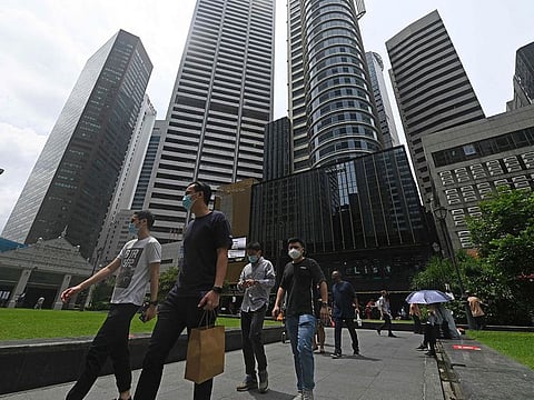 Office workers walk out during their lunch break at Raffles Place financial business district in Singapore.