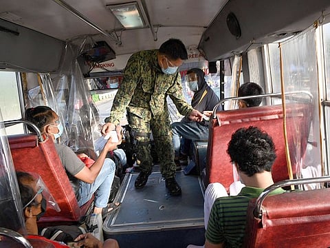 A police officer inspects documents of passengers travelling from nearby Rizal province inside a bus at a border checkpoint in Quezon City, suburban Manila on August 6, 2021, after authorities imposed another lockdown in the metropolis due to the threat of the Delta variant of COVID-19.